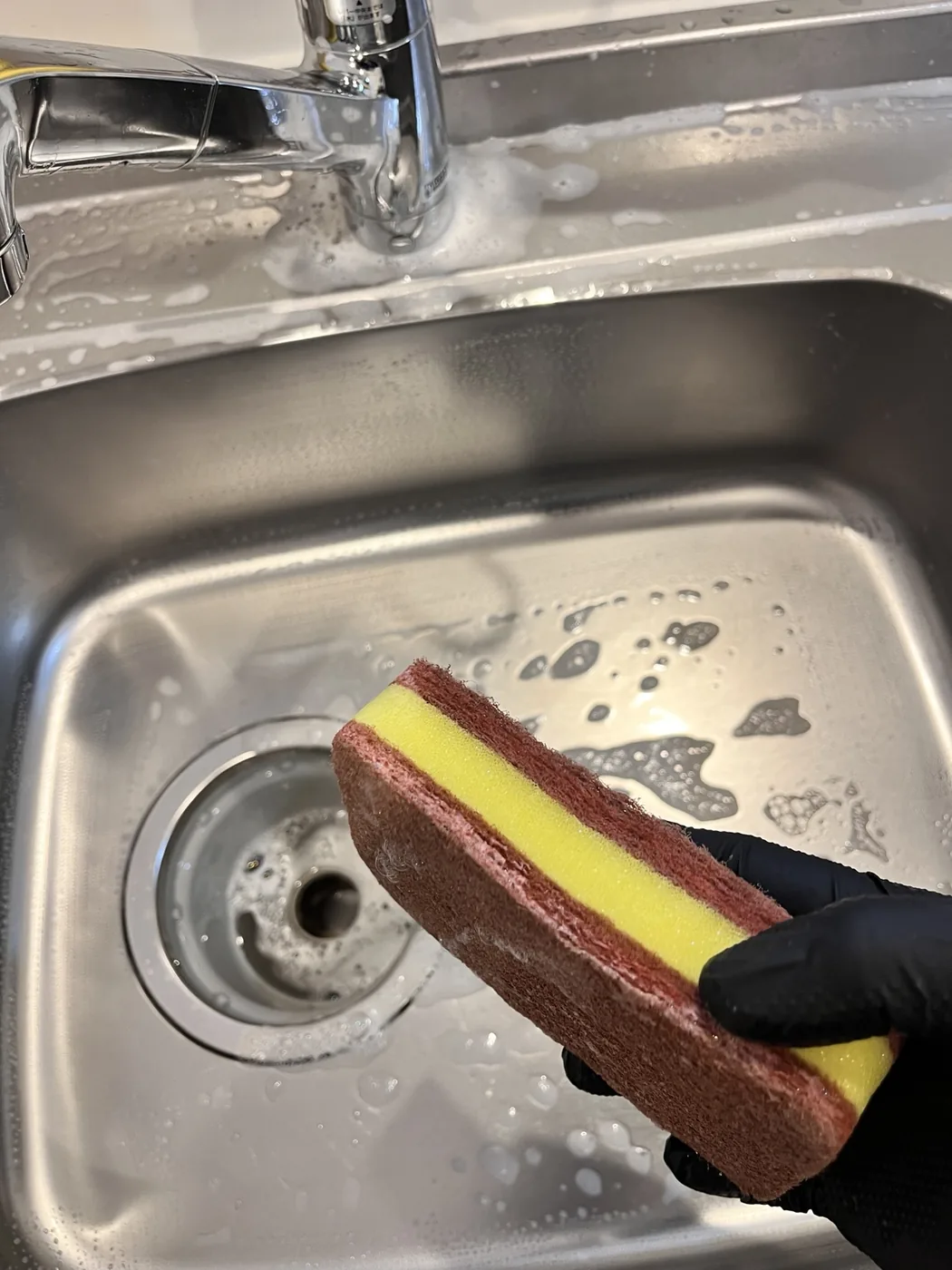 キッチンシンクを手作業で清掃している写真