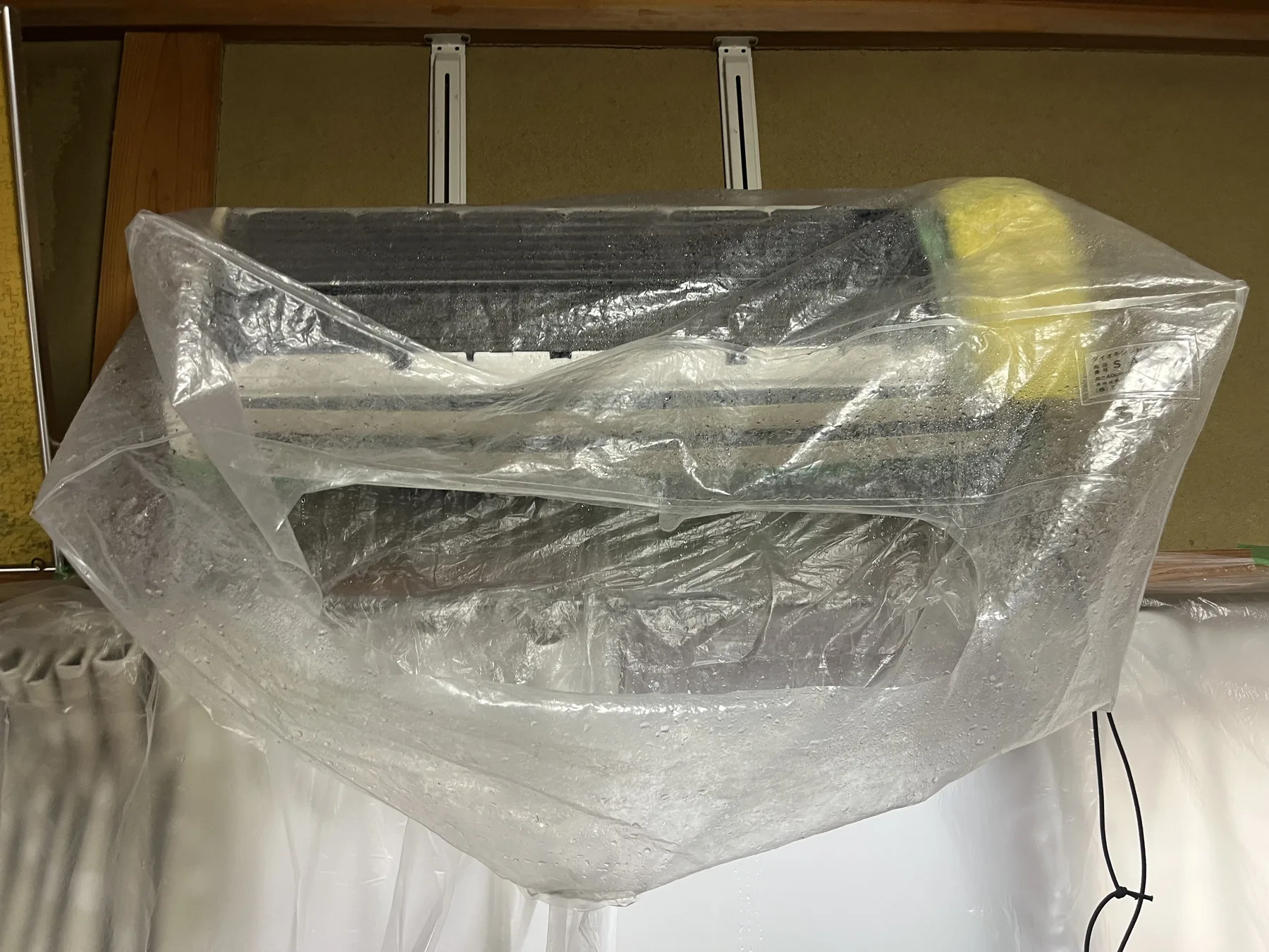 分解したエアコンに洗浄用の養生を取り付けた状態